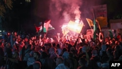 Протестувальники піднімають палестинські прапори та портрет Мохаммеда Дейфа, керівника бригад Аль-Касам, військового крила ХАМАС, під час мітингу біля входу в комплекс посольства Франції в Бейруті вранці 18 жовтня 2023 року