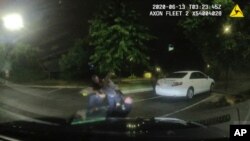 Esta captura de video de una cámara de un auto policial, provista por la Policía de Atlanta, muestra a Rayshard Brooks, en el centro, forcejeando con los agentes de policía en el estacionamiento de un restaurante Wendy's. Atlanta, Junio 13 de 2020. 