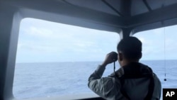 Anggota Badan Keamanan Laut (Bakamla) tampak menggunakan teropong untuk mengawasi pergerakan kapal penjaga pantai China di Laut Natuna Utara, pada 24 Oktober 2024. (Foto: Bakamla via AP)