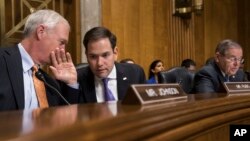 El senador Marco Rubio, republicano por Florida, conversa con el seandor Ron Johnson, republicano por Wisconsin (izquierda) mientras el senador Bob Menéndez, demócrata por Nueva Jersery (derecha) observa durante la audiencia de la subcomisión de asuntos del Hemisferio Occidental del Seando el martes, 9 de enero de 2018, en el Capitolio, en Washington, D.C.