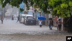 Gente camina por una calle inundada por las lluvias de la tormenta tropical Franklin en Santo Domingo, República Dominicana, el martes 22 de agosto de 2023.