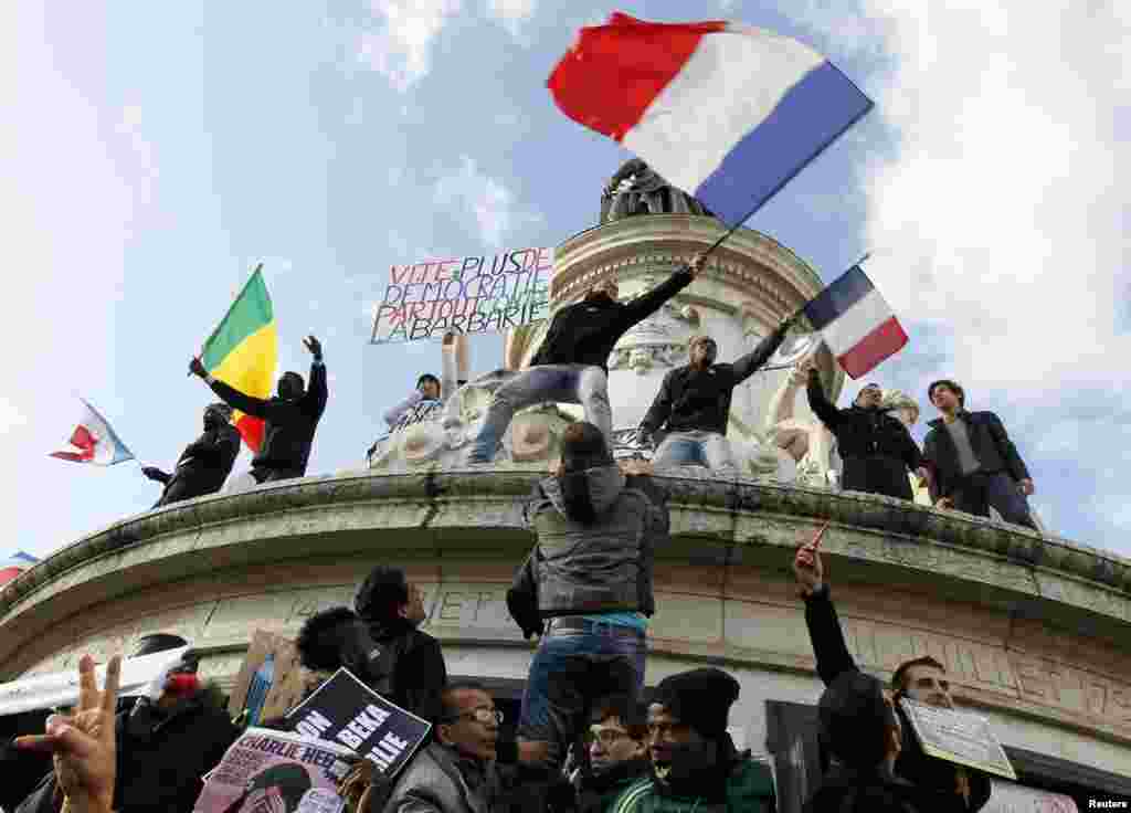 People holding a poster reading "Quick more democracy everywhere against barbarism" take part in a solidarity march in the streets of Paris, Jan. 11, 2015.
