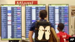 Penumpang memeriksa papan jadual keberangkatan di bandara internasional Miami, 7 September 2017. 