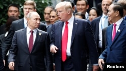 U.S. President Donald Trump and Russia's President Vladimir Putin talk as Vietnam's President Tran Dai Quang, right, looks on, during the photo session at the APEC Summit in Danang, Vietnam, Nov. 11, 2017.