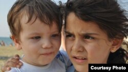 Manar Qarra, manajer umum Panti Asuhan Selam di Gaziantep, Turki, mengambil foto dua anak di dari panti asuhan ketika berkunjung ke pantai.