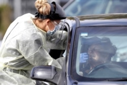 FILE - Medical staff test a shopper in her car who volunteered at a pop-up community COVID-19 testing station at a supermarket carpark in Christchurch, New Zealand, Friday, April 17, 2020.