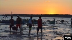 At sunset on the shores of Masinloc town fishermen return from a day of fishing nearby in the South China Sea, while others head out for overnight fishing, Masinloc, Philippines, Nov. 8, 2015. (S. Orendain/VOA)