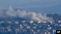 Asap mengepul dari sela-sela rumah di Kota Metula di perbatasan Israel utara yang terkena tembakan Hizbullah, terlihat dari sisi kota Marjayoun, Lebanon, Lebanon, Sabtu, 22 Juni 2024. (Foto: AP)