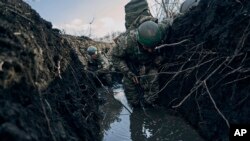 Sejumlah tentara Ukraina bersembunyi di dalam parit untuk menghindar dari serangan Rusia di garis depan pertempuran di dekat Bakhmut, Donestk, Ukraina, pada 5 Maret 2023. (Foto: AP/Libkos)