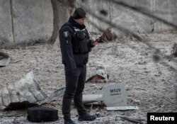 Un oficial de policía se encuentra cerca de partes del dron en el sitio de un edificio destruido por un ataque con un dron ruso, mientras continúa su ataque contra Ucrania, en Kyiv, Ucrania, el 14 de diciembre de 2022. La inscripción dice "Para Ryazan". REUTERS/Gleb Garanich