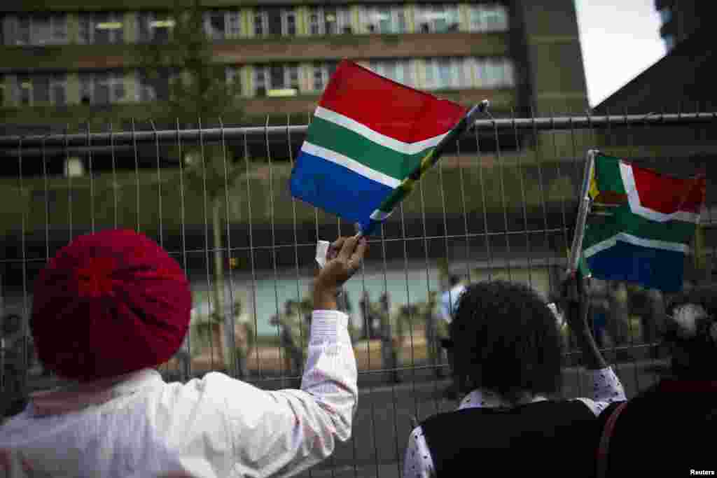 Mulheres abanam bandeiras sul-africanas antes do cortejo fúnebre do ex Presidente Nelson Mandela em Pretoria, Dez. 11, 2013.
