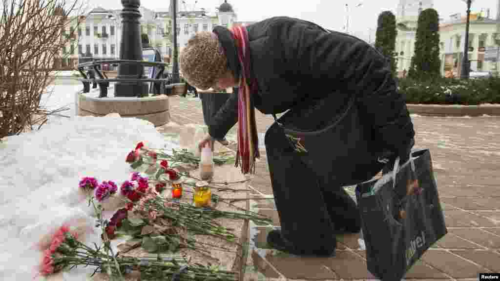 Une femme allume une bougie de condoléances à l'ambassade française à Minsk, en Biélorussie, le 8 janvier 2015.