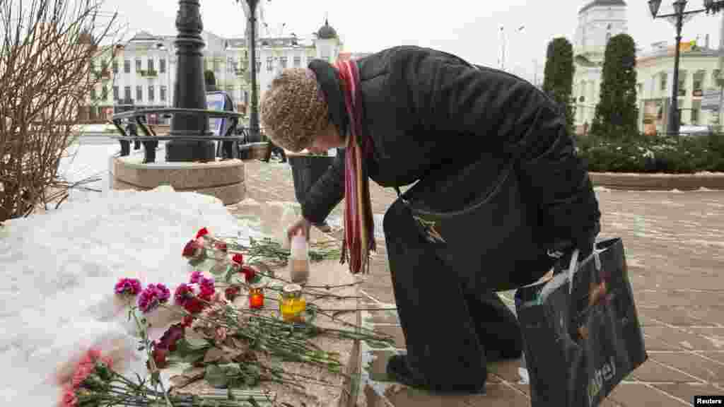 A woman lights a condolence candle at the French embassy in Minsk, Belarus, Jan. 8, 2015.