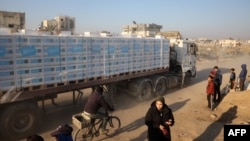 People watch as a truck loaded with humanitarian aid drives through a devastated street in Khan Younis in the southern Gaza Strip on Jan. 30, 2025.
