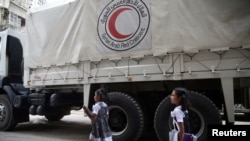Twin girls walk near a Red Crescent aid convoy carrying urgent medical supplies in the rebel held besieged town of Douma, eastern Ghouta in Damascus, Syria, May 26, 2016. 