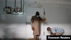 A worker prepares to store boxes of vaccines in a cold room as the country receives its first batch of coronavirus disease (COVID-19) vaccines under COVAX scheme, in Accra