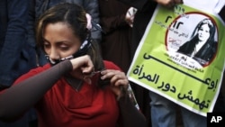 Egipćanka seče kosu u znak protesta zbog novog ustava, na demonstracijama na trgu Tahrir, 25. decembra 2012. Na plakatu pored nje piše: "ne marginalizovati položaj žena."