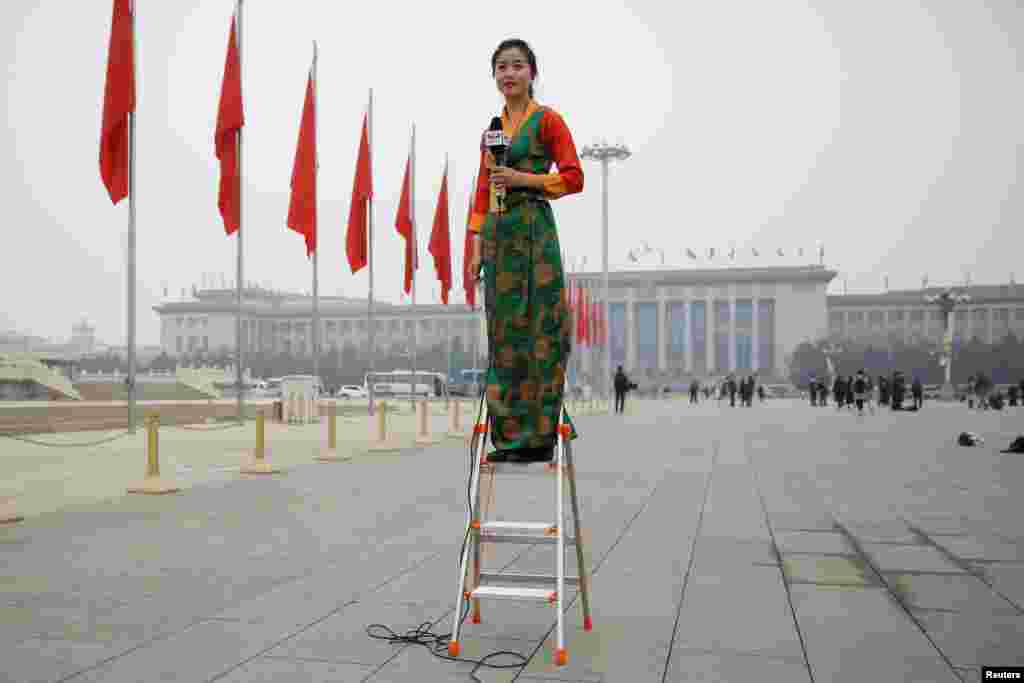 2018年3月3日,中国人民政治协商会议在北京开幕之前,在人民大会堂外的空荡荡的天安门广场,一位记者站在梯子上做报道。在人民大会堂开重要大会时,人民大会堂外面的广场经常是戒备森严,没有多少人民。当天北京雾霾严重,PM2.5指数超过200,非常不利于健康。看来今年当局并没有刻意营造“两会蓝”。