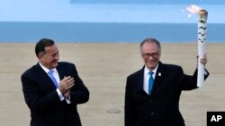 Rio 2016 organizing committee president Carlos Nuzman, right, holds a torch with the Olympic Flame as the head of Greece's Olympic Committee, Spyros Capralos applauds during the handover ceremony at Panathinean stadium in Athens on April 27, 2016.