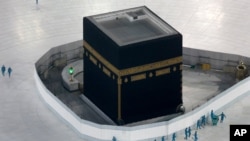 FILE - Workers disinfect the grounds around the Kaaba, a cubic building at the Grand Mosque in the Muslim holy city of Mecca, Saudi Arabia, March 7, 2020.
