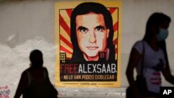 ARCHIVO - Peatones caminan cerca de un gran cartel del empresario colombiano Alex Saab en Caracas, Venezuela, en septiembre de 2021.