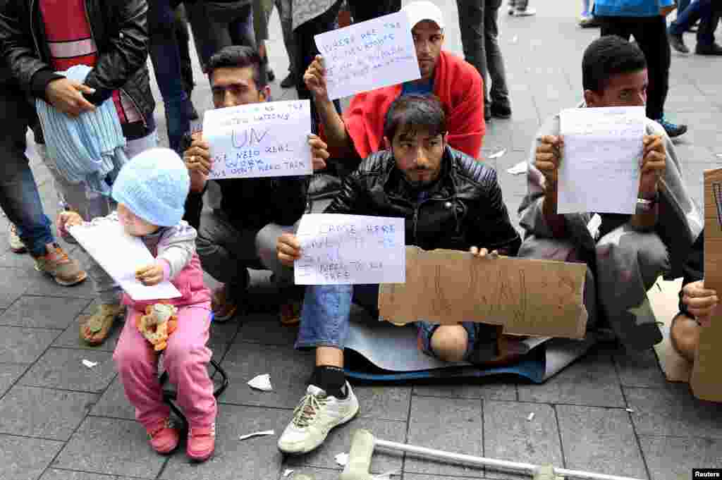 Migrants hold signs in front of Keleti railway station in Budapest, Hungary, Sept. 4, 2015.