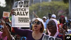 Female residents hold up images of black teenager Trayvon Martin and a packet of Skittles candy during a rally demanding justice for his killing in Miami, Florida April 1, 2012. 