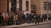 Migrantes hacen fila a la intemperie en el exterior de un centro de ayuda habilitado en la escuela primaria Santa Brígida, el 5 de diciembre de 2023, en Nueva York.