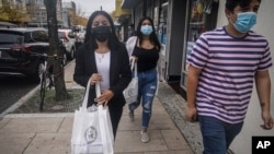 FILE - Emili Prado, 21, left, Christine Cuenca, 18, and Jason Jimenez, 19, campaign to turn out the vote in the largely Hispanic community of Port Richmond in Staten Island, N.Y., Oct. 23, 2020.