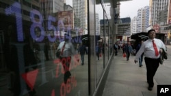 A man walk past a bank electronic board showing the Hong Kong share index at Hong Kong Stock Exchange Thursday, Feb. 11, 2015.