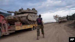 Израелски војник работи товари тенк на транспортен камион во област во близина на израелско-либанската граница, гледано од северен Израел, 4 декември 2024 година
