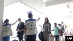 En un control de inmigración en Myawaddy, Birmania, cerca de la frontera tailandesa, funcionarios toman la temperatura a quienes arriban al lugar, como medida para reducir el riego de contagio.