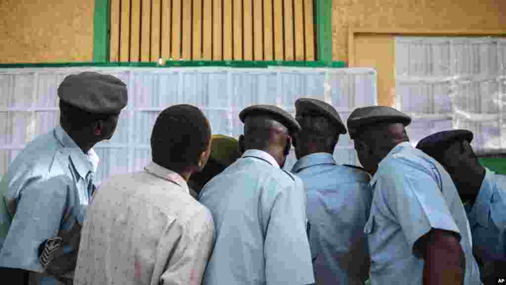 Des membres des forces de sécurité soudanaises cherchent leurs noms sur une liste électorale à l’extérieur d'un bureau de vote où ils doivent voter, au premier jour des élections présidentielle et législatives du Soudan, à Khartoum, au Soudan, le 13 avril 2015.
