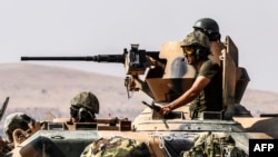 Tentara Turki duduk di atas tank menuju Suriah dari kota perbatasan Karkamis di Gaziantep (27/8). (AFP/Bulent Kilic)