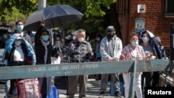 La gente reza durante una misa católica celebrada fuera de un banco de alimentos en la Iglesia de San Bartolomé, durante el brote de la enfermedad por coronavirus (COVID-19 en Nueva York, EE.UU. )