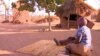 Women sit outside their huts on the outskirts of Harare, Zimbabwe. (S. Mhofu/VOA)
