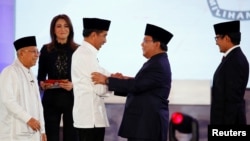 Indonesia's presidential candidate Joko Widodo shakes hands with his opponent Prabowo Subianto as their running mates Ma'ruf Amin and Sandiaga Uno smile after a televised debate in Jakarta, Indonesia, Jan. 17, 2019. 