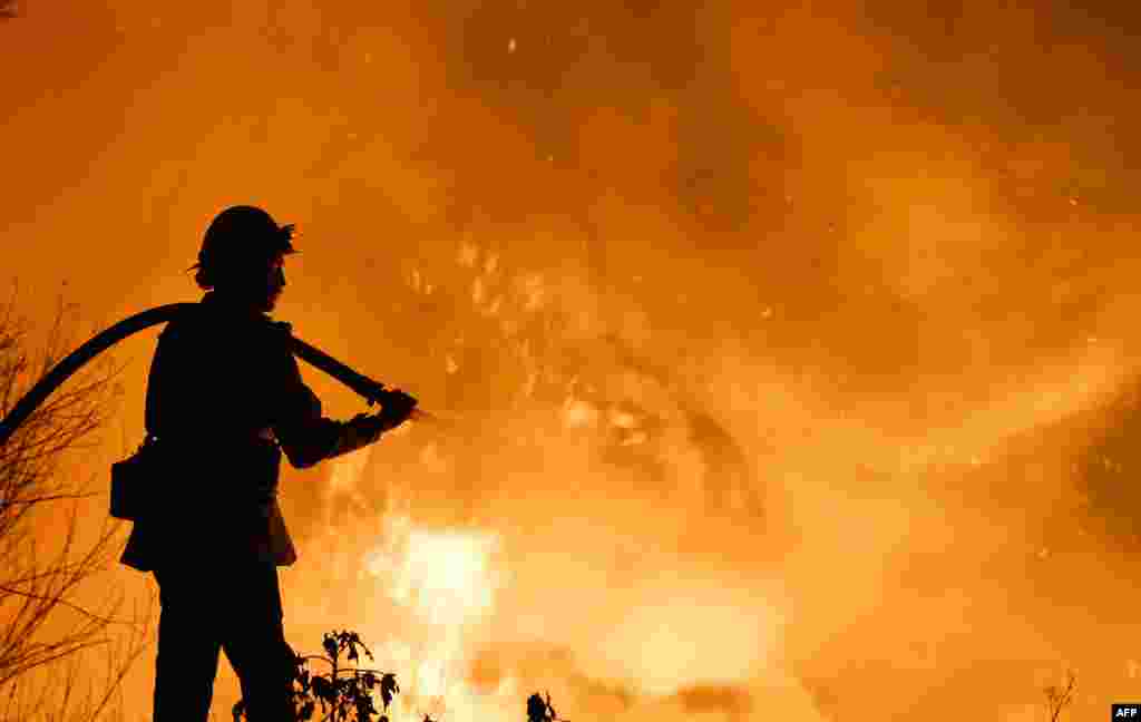 A firefighter battles a wildfire as it burns along a hillside near homes in Santa Paula, California, Dec. 5, 2017.