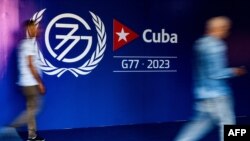 2023年9月13日，哈瓦那新闻发布厅开幕期间，人们走在77国集团+中国峰会的标志附近. (法新社)