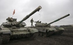 FILE - A member of the self-proclaimed Donetsk People's Republic forces walks on top of a tank during a drill outside Torez, Donetsk region, Ukraine, Sept. 14, 2015.