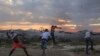 Para demonstran melemparkan batu ke arah pihak berwenang Venezuela, di perbatasan antara Brasil dan Venezuela, Sabtu, 23 Februari, 2019. (Foto: dok).