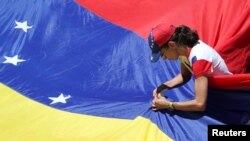 Una seguidora del líder de la oposición venezolana Juan Guaidó, a quien muchas naciones reconocen como el gobernante interino legítimo del país, fija una bandera durante una manifestación contra el gobierno del presidente Nicolás Maduro. [Archivo]