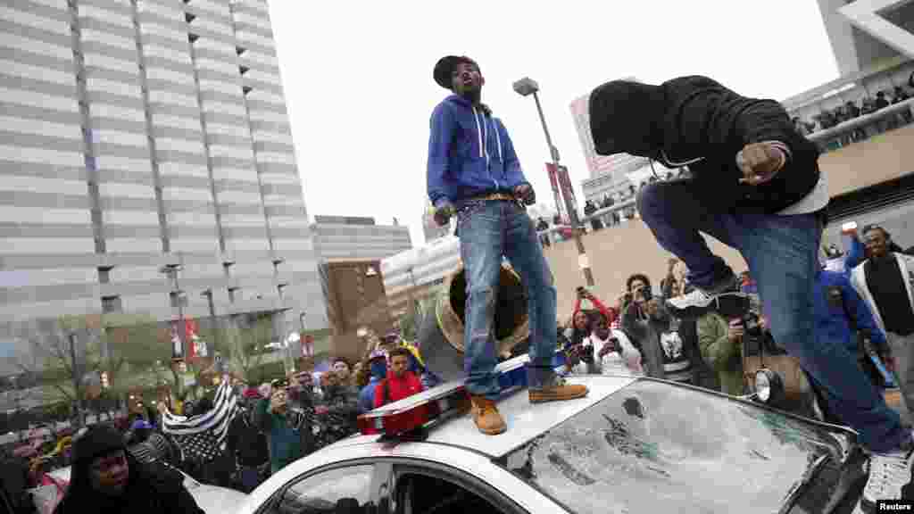 Para demonstran melompati mobil polisi dalam protes atas kematian Freddie Gray di tahanan polisi di Baltimore (25/4). (Reuters/Shannon Stapleton)