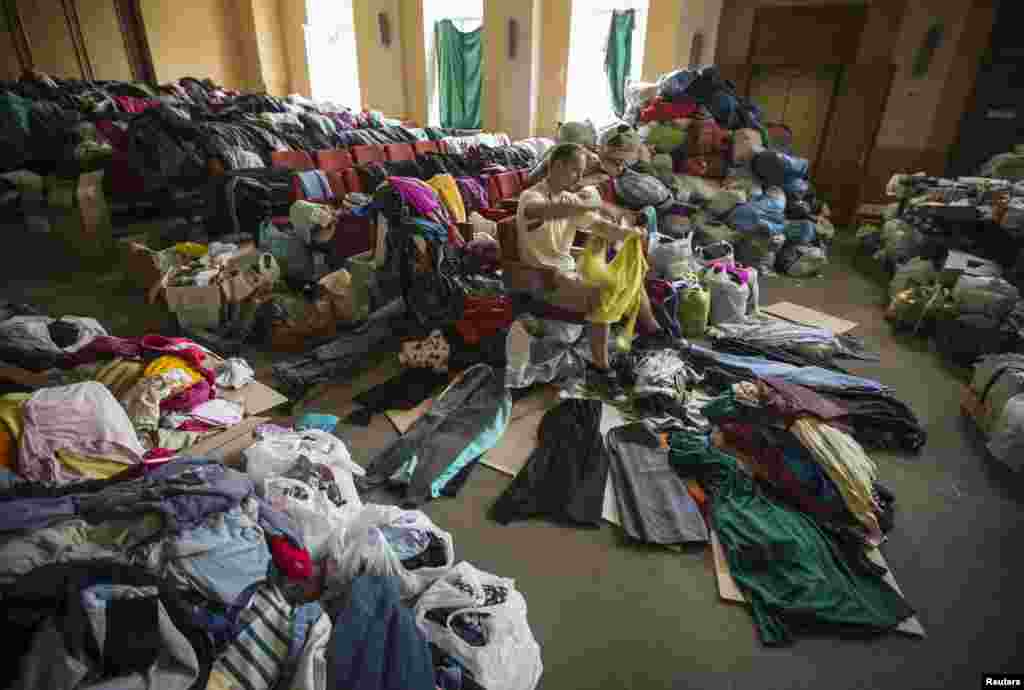 A man sorts donated clothes at a former concert hall converted into a center for collecting humanitarian aid for refugees in Donetsk, Ukraine, June 26, 2014.