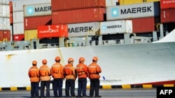 Trabajadores frente a un barco de contenedores en un puerto en Qingdao, en la provincia oriental china de Shandong. Foto del 8 de abril de 2018.
