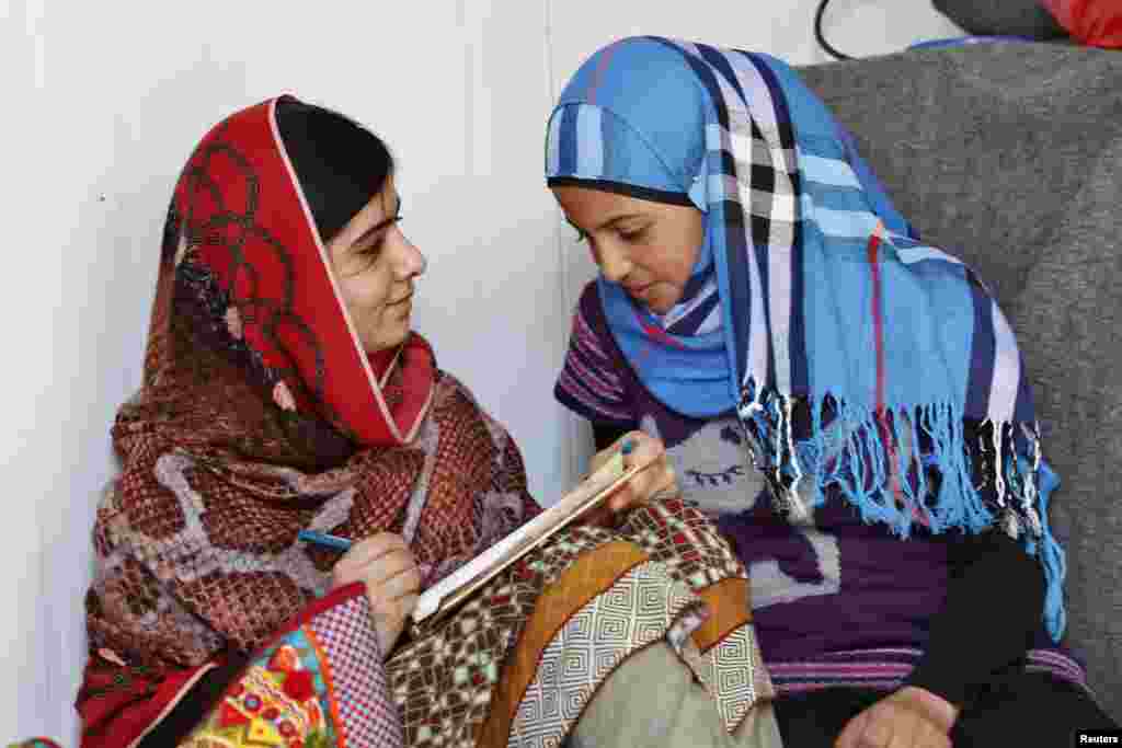 Pakistani teenage activist Malala Yousafzai (left), who was shot in the head by the Taliban for campaigning for girls' education, talks to Syrian refugee Mazoon Rakan, 16, about Mazoon's experience in the camp during her visit to the Zaatri refugee camp, in Jordanian city of Mafraq, near the border with Syria, Feb. 18, 2014. 