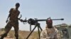 FILE - Somali government soldiers looking out from a machine gun mounted pick-up truck at Tobanka Buundo in the lower Shabelle region, near the Somalian capital Mogadishu, March 6, 2014.