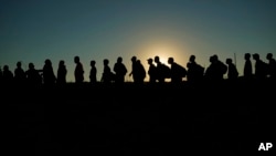 Los migrantes que cruzaron el Río Grande y entraron a EEUU desde México hacen fila para ser procesados por la Oficina de Aduanas y Protección Fronteriza de los EE. UU., el 23 de septiembre de 2023, en Eagle Pass, Texas.