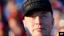 FILE - Tesla and SpaceX CEO Elon Musk listens as Republican presidential nominee former President Donald Trump speaks at a campaign event at the Butler Farm Show, Oct. 5, 2024, in Butler, Pa.