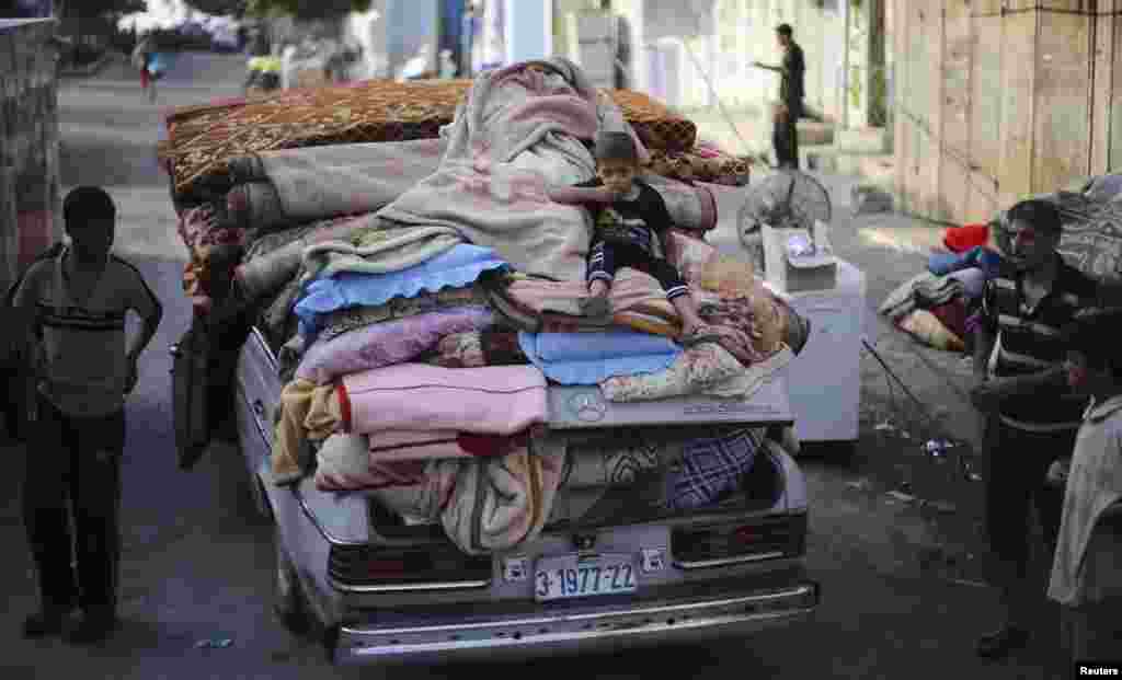 A Palestinian boy sits atop a car loaded with his family's belongings near their house, which was hit by an air strike, in Rafah in the southern Gaza Strip, Aug. 26, 2014.